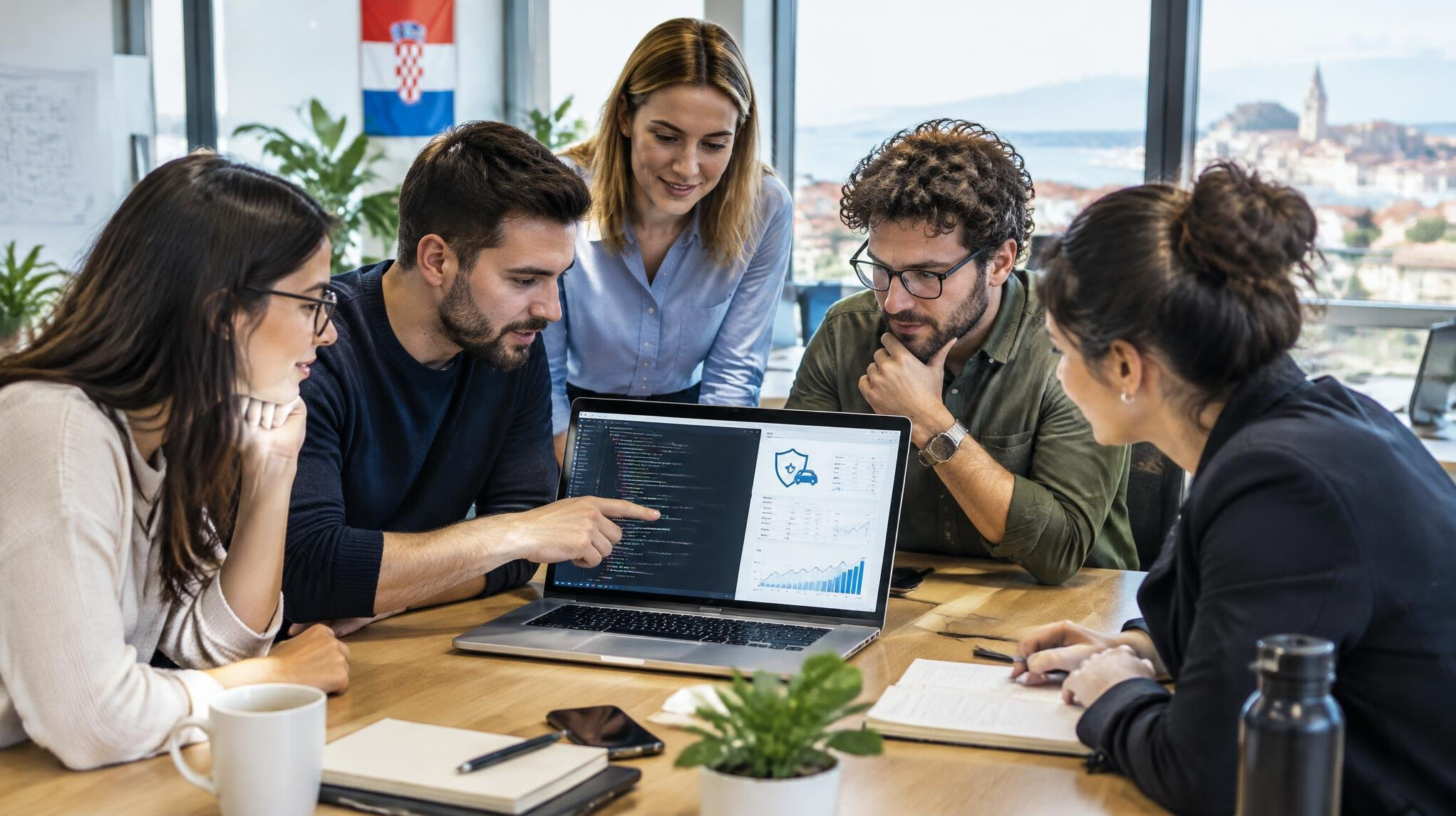 Team of software developers reviewing insurance data on a laptop screen in a modern office